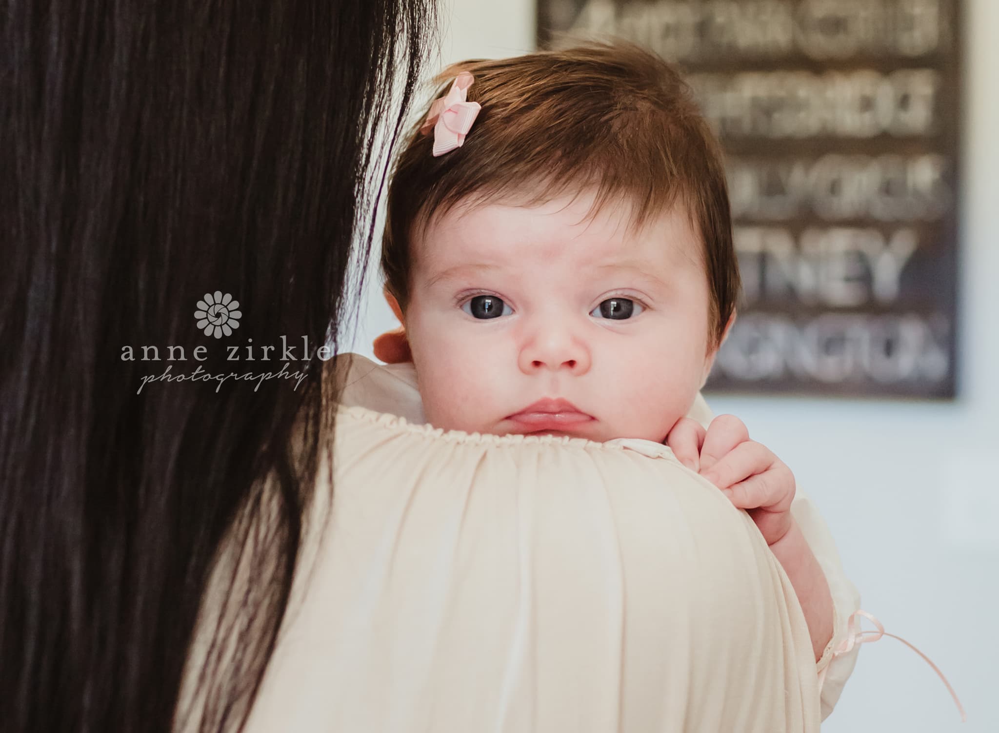 newborn girl with hair looking over moms shoulder Mooresville and Lake Norman newborn baby photographer